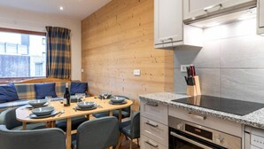 Una cocina moderna con pared de madera, una mesa de comedor con sillas y electrodomésticos integrados.