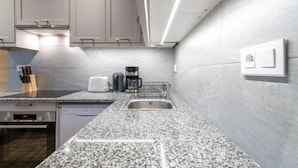 Una cocina moderna con encimeras de granito, electrodomésticos de acero inoxidable y horno empotrado.