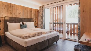 A bedroom with a wooden headboard, a large bed with beige bedding, a nightstand, and a wooden floor.