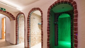 Ein Flur mit Bogenöffnungen, von denen eine in einen Raum mit grüner Beleuchtung führt.