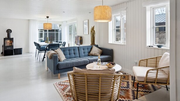 A spacious living room with a blue sofa, wicker chairs, a dining area with a table, and a fireplace. - "Elizabeta" - 175m from the sea by Interhome (Hals)