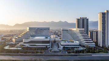 Un moderno complejo hotelero con varias edificaciones, un patio central y vistas a montañas distantes.