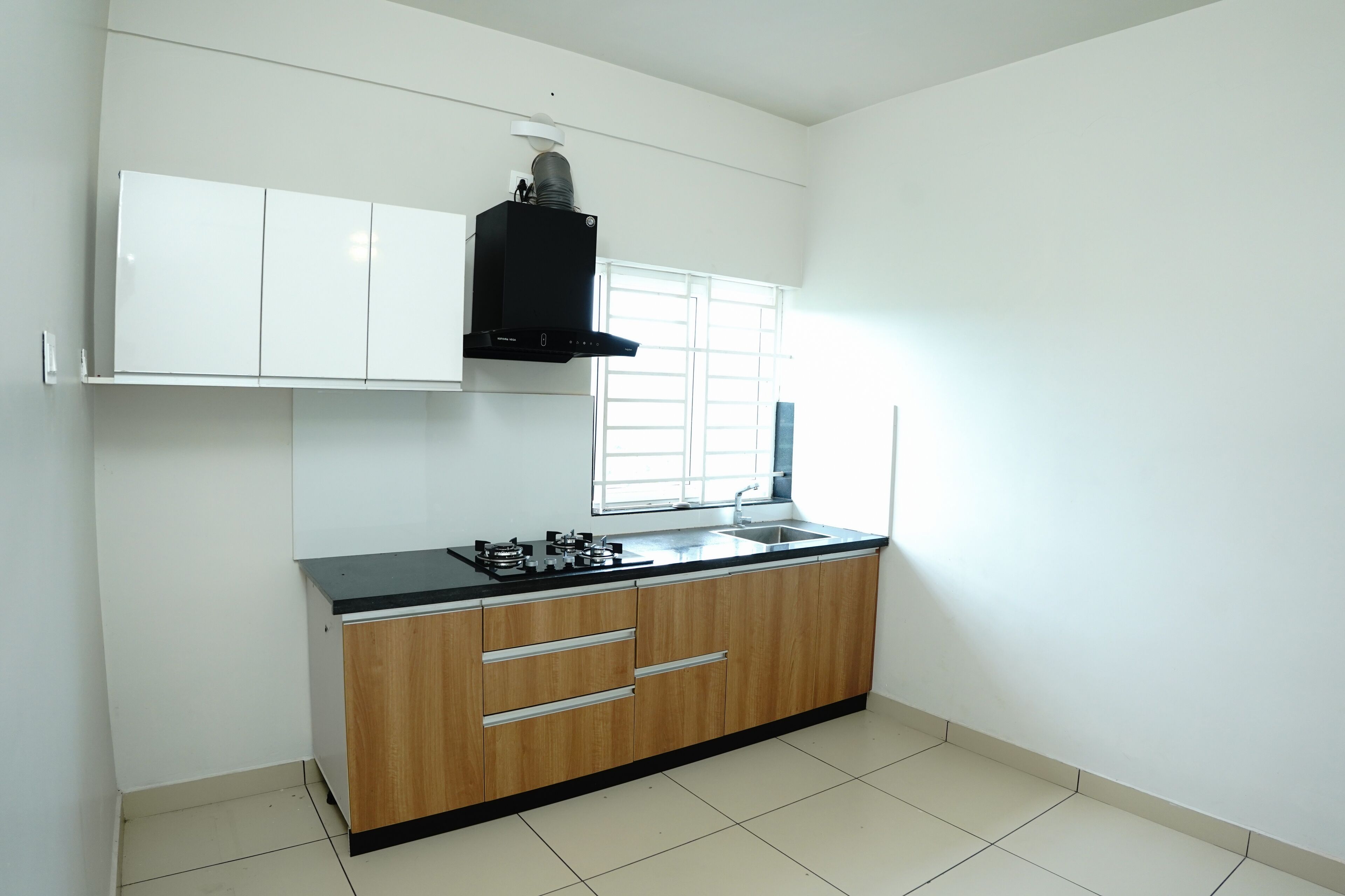 A kitchen with white cabinets, a black countertop, and a window with blinds.