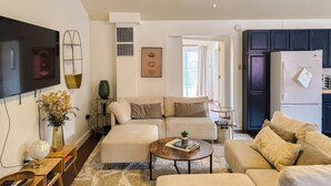 A living room with a sofa, coffee table, TV, and a small side table with a globe and books.