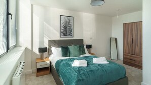 Une chambre à coucher moderne avec un lit, des tables de chevet, un miroir et une armoire.
