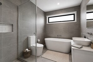 A modern bathroom with a glass shower enclosure, a freestanding bathtub, a sink, and a toilet.