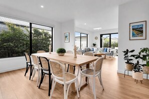Ein modernes Interieur mit Essbereich, Sofas und Topfpflanzen.