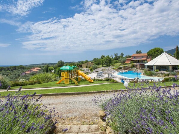 Un terrain de jeux avec des toboggans, une piscine et une vue sur la campagne.
