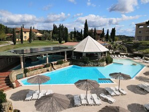 Ein Resort mit einem großen Swimmingpool, Liegestühlen und einer überdachten Pergola.