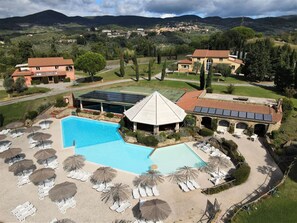 Ein Resort mit großem Schwimmbad, Liegestühlen und einem überdachten Bereich mit Solaranlage.