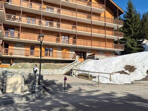 A multi-story hotel with balconies, stone walls, and a snow-covered slope.