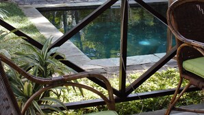 A pool area with a geometric pool design, surrounded by lush greenery and wicker furniture. - Villa Sirandane Baie Du Tombeau (Tombeau Bay)