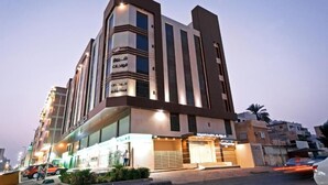 A modern hotel with a prominent entrance, large windows, and a well-lit facade. - Asis Rise شروق الواحات الراقية للشقق المخدومة (Jeddah)