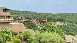 Área residencial com vários edifícios de apartamentos, cercada por vegetação e colinas.