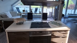A modern kitchen with a central island, built-in oven, and a large window overlooking a patio area.