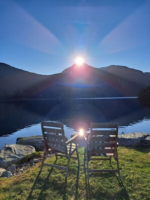 Two wooden chairs facing a calm lake with a mountain in the background and the sun shining brightly. - Idyllische Hütte am Dalsfjord (Møre og Romsdal)