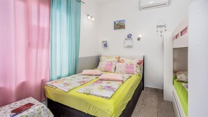 Un dormitorio con cama, mesita de noche, armario y ventana con cortinas.