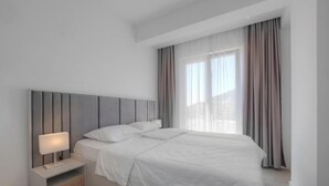 Une chambre à coucher moderne avec un lit, une table de chevet et une fenêtre avec des rideaux.