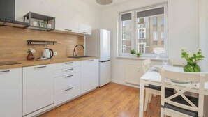A modern kitchen with white cabinets, a wooden countertop, and a window with a view of buildings. - Functional Apartment in Poznan | Place to Work (Poznan)