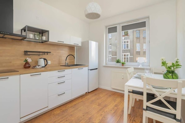 Eine moderne Küche mit weißen Schränken, einer Holzausziehtheke und einem Fenster mit Blick auf Gebäude.