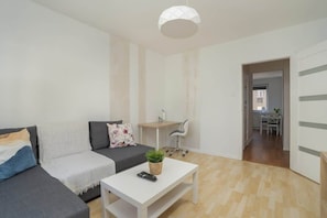 Ein modernes Wohnzimmer mit einem grauen Sofa, einem weißen Couchtisch und einem kleinen Schreibtisch.