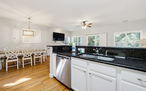A modern kitchen with a black granite countertop, white cabinetry, and a built-in dishwasher. - Resort Access & Golf Cart Included! (Fripp Island)