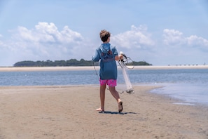 A person walking on a sandy beach holding a fishing net. - Resort Access & Golf Cart Included! (Fripp Island)