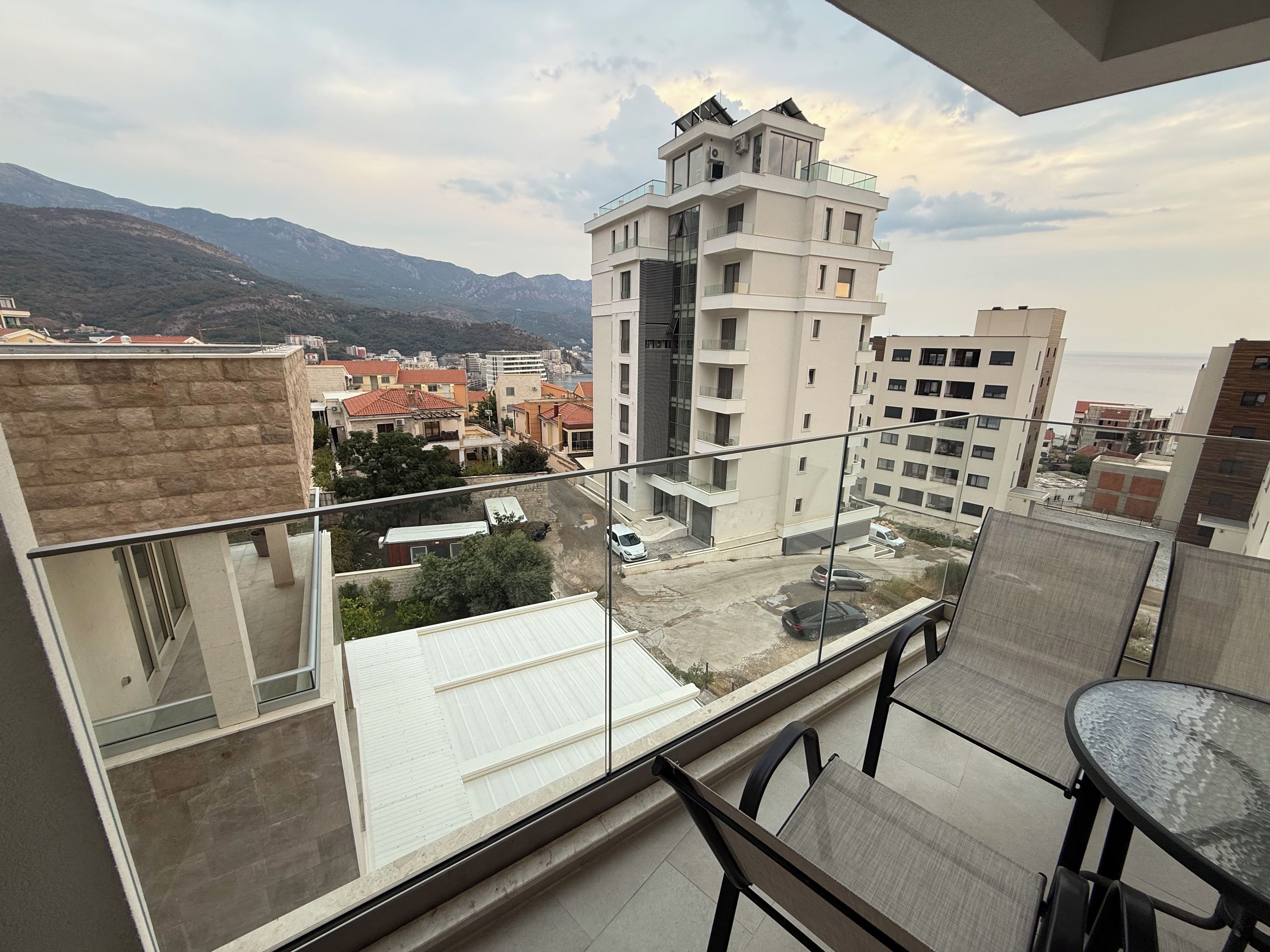 Un balcón con vista a un paisaje urbano, incluyendo un edificio alto y montañas.
