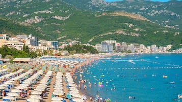 Une plage avec de nombreux parasols et des gens qui se baignent.