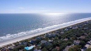 A coastal residential area with houses, a beach, and a clear sky.