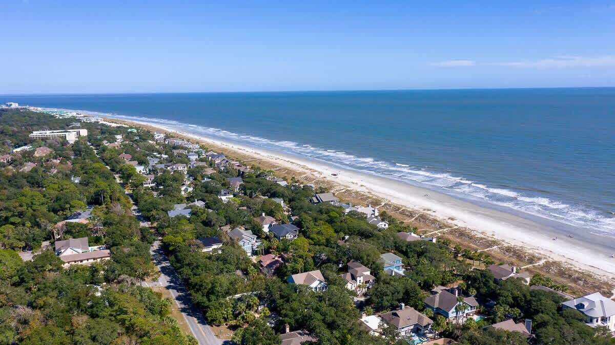 Luftaufnahme einer Küstenwohngegend mit Häusern, Strand und dem Meer.