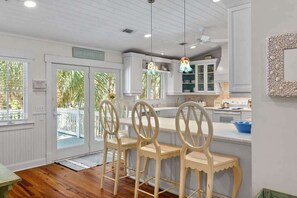 A kitchen with white cabinets, a wooden bar counter, and a hanging light fixture.