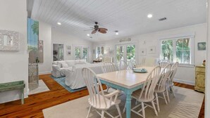 A dining area with a table and chairs, a ceiling fan, and a view of the outdoors.