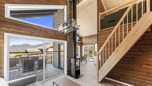 A modern interior with a stone fireplace, wooden floors, and a staircase.