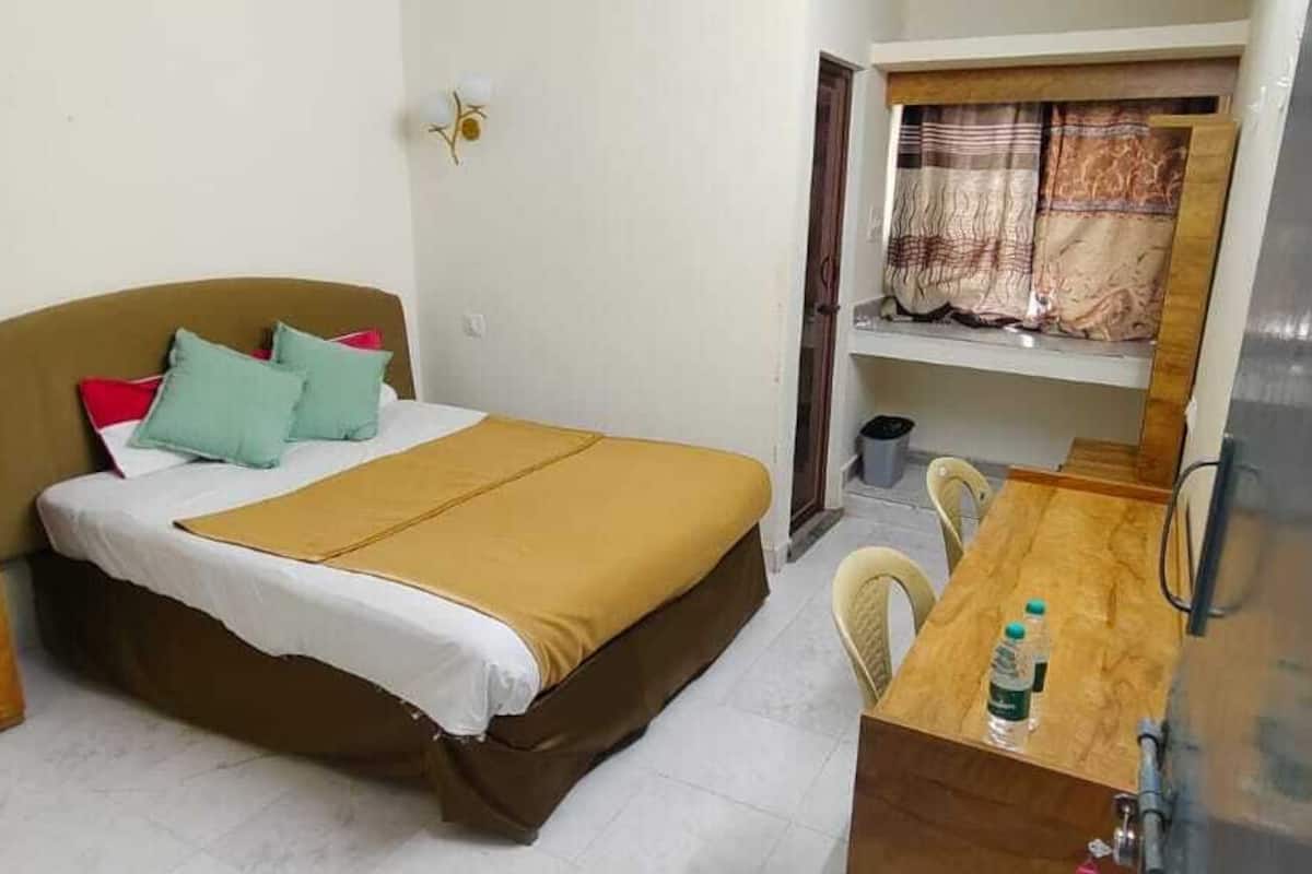 A small, compact room with a bed, a desk, and a chair.