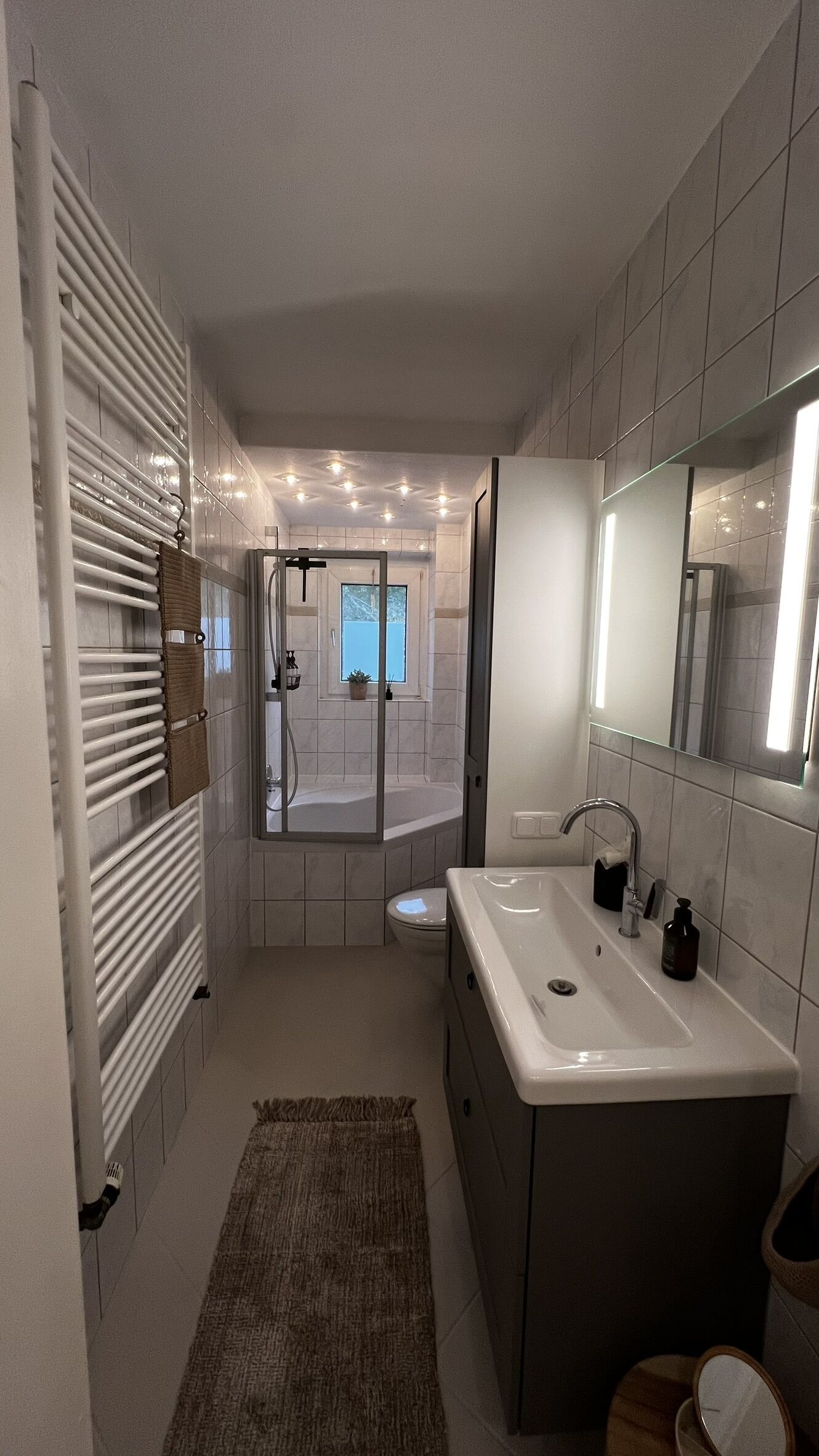 A modern bathroom with a large sink, mirror, and towel rack.