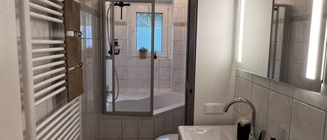 A modern bathroom with a large sink, mirror, and towel rack.