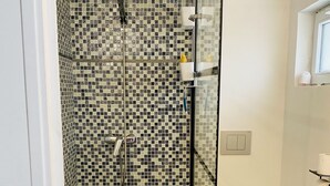 A bathroom with a shower area featuring mosaic tile walls, a toilet, and a sink. - Abrilove Petit Studio de 15 m², Coin Cuisine, Salle de Bain (Castres)