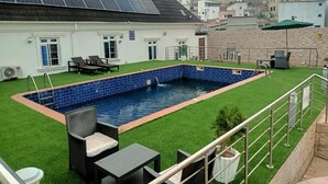A residential building with a swimming pool, solar panels, and outdoor furniture.
