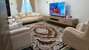 A living room with a beige sofa, a patterned rug, and a television on a wooden stand.