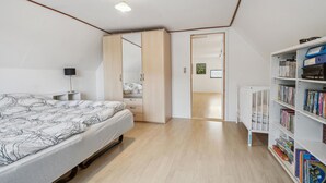 Ein Schlafzimmer mit Bett, Nachttisch, Bücherregal und Kleiderschrank.