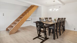 Ein Essbereich mit einer Holztreppe, einer Chandelüster und einem Tisch für sechs Personen.