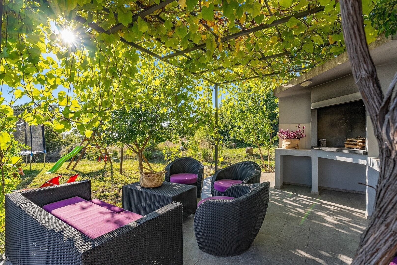 Une terrasse extérieure aménagée avec des meubles en osier et un espace barbecue.