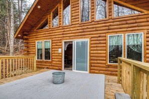 A log cabin with multiple windows, a deck, and a metal bucket.