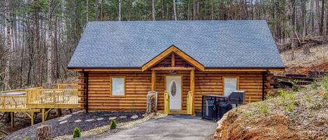 Une cabane en rondins avec un porche, une porte et une petite terrasse avec des chaises.