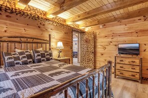 Un dormitorio de cabaña de madera con una cama, una mesita de noche, una lámpara, un televisor y un armario.