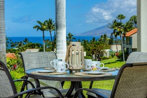 A table set for tea with a view of the ocean and palm trees.