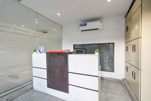 Uma receção com divisória de vidro, ar condicionado fixado na parede e conjunto de armários de arquivo bege.