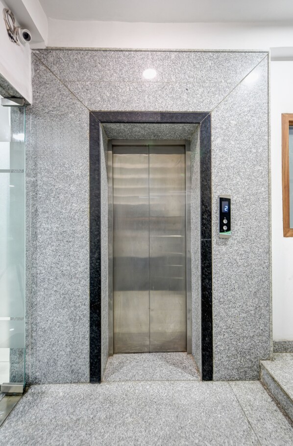 Um elevador com parede de granito e visor digital exibindo o número 2.