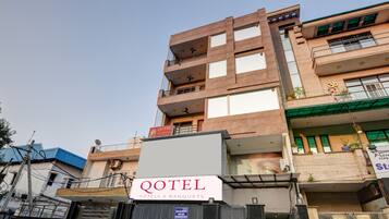 Un edificio de varios pisos con un letrero que dice "QOTEL Hotels & Banquets" en la planta baja.